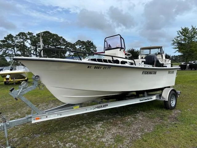 The Image of 2021 May-Craft 1800 Skiff boat on trailer, labeled "FISHINATOR," parked on grass. - 1