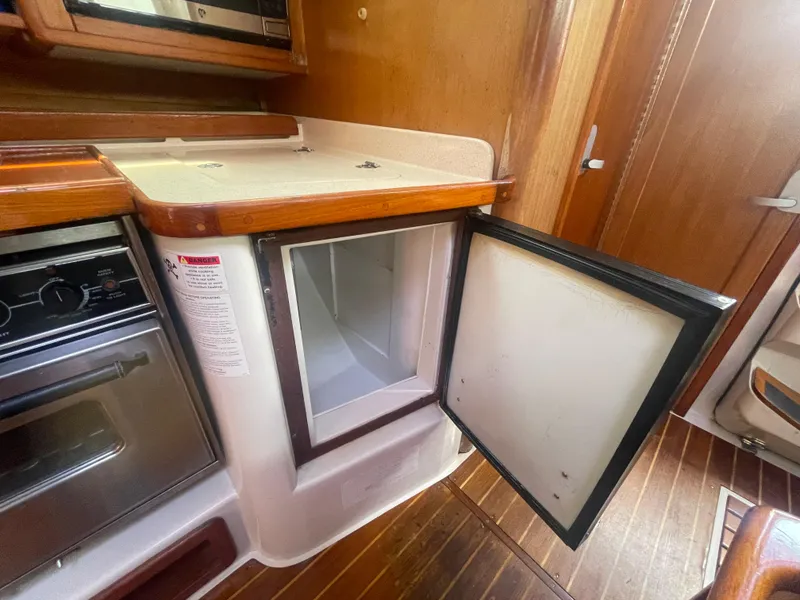 Slide: The Image of 1999 Catalina 42 MkII yacht interior with open fridge and wooden cabinetry. - 6