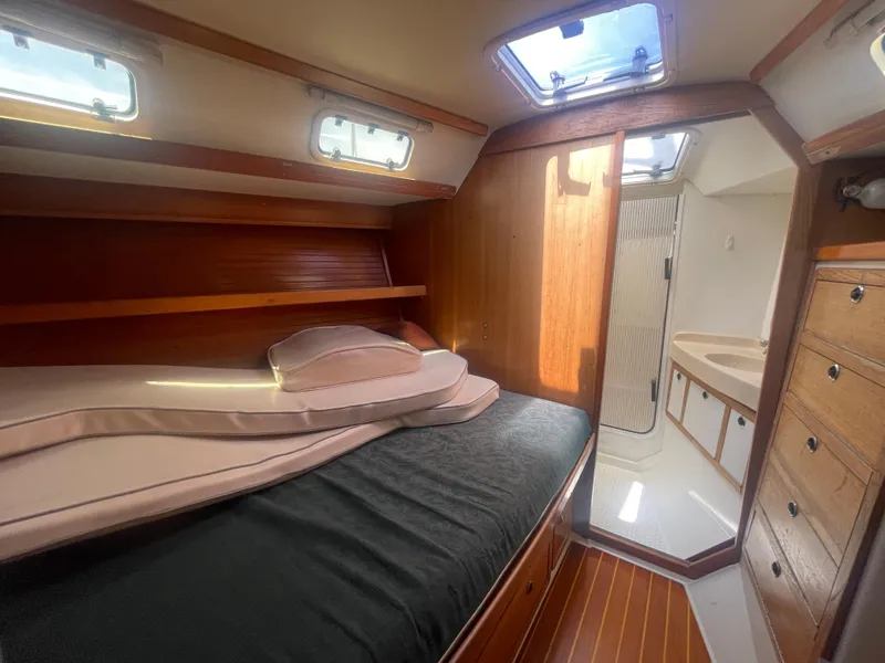 Slide: The Image of 1999 Catalina 42 MkII cabin interior with bed, wooden cabinetry, and adjacent bathroom. - 8