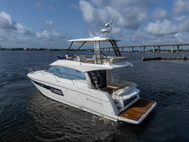 Slide: The Image of 2019 Prestige 460 yacht cruising on a calm river under a cloudy sky. - 12