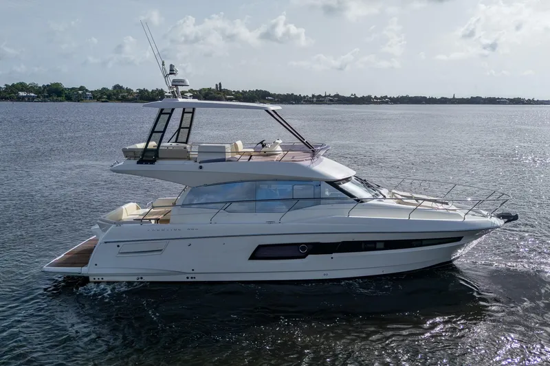 Slide: The Image of 2019 Prestige 460 yacht cruising on calm waters under a cloudy sky. - 13