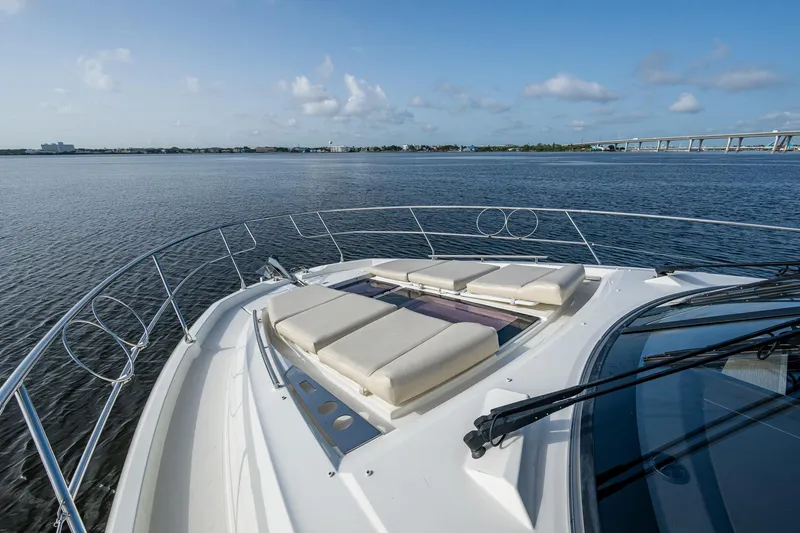 Slide: The Image of 2019 Prestige 460 yacht with sun loungers on deck, overlooking calm waters and distant bridge. - 18