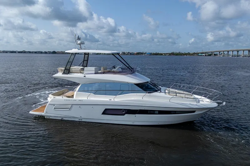 Slide: The Image of 2019 Prestige 460 yacht cruising on open water under a partly cloudy sky. - 5