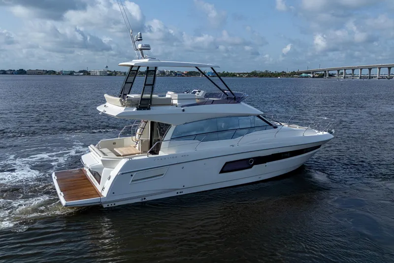 Slide: The Image of 2019 Prestige 460 yacht cruising on a calm river under a cloudy sky. - 6