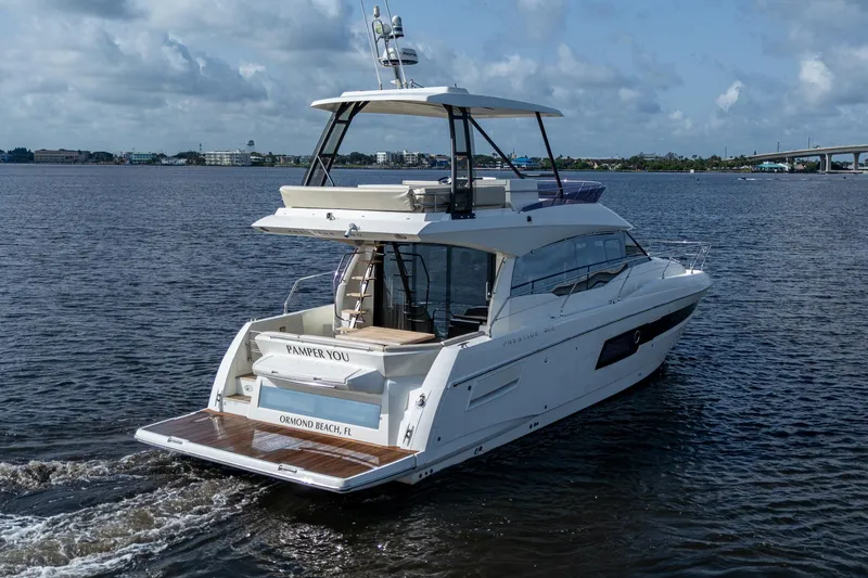 Slide: The Image of 2019 Prestige 460 yacht cruising on calm waters under a partly cloudy sky. - 7