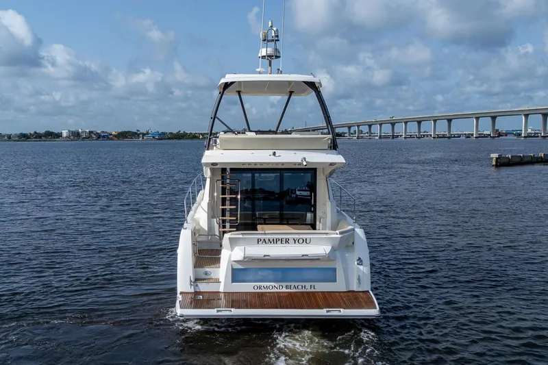 Slide: The Image of 2019 Prestige 460 yacht cruising near a bridge under a cloudy sky. - 8