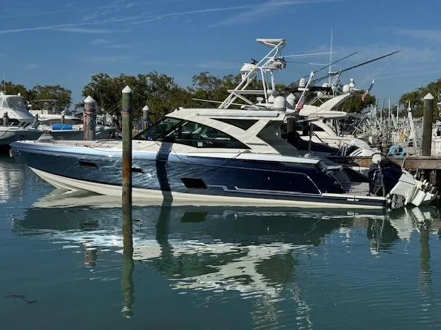 Slide: The Image of 2022 Formula 430 Super Sport Crossover boat docked in a marina under clear blue skies. - 2