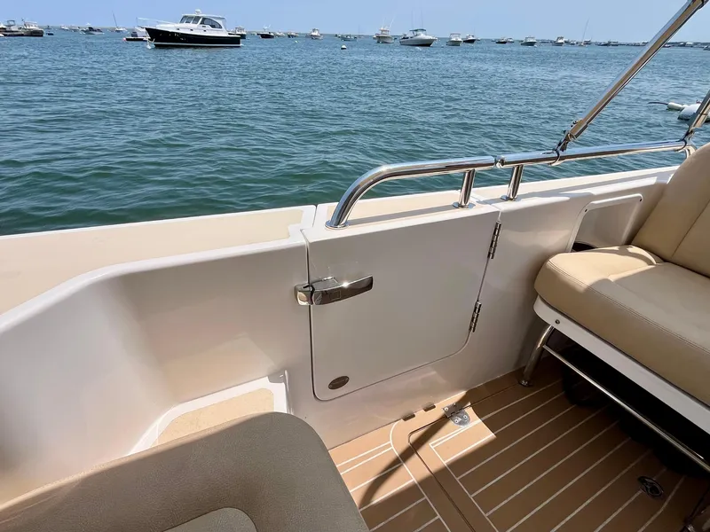 Slide: The Image of 2019 MJM 35z boat interior with beige seating, overlooking a calm sea with distant boats. - 12