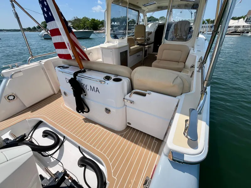 Slide: The Image of 2019 MJM 35z boat with spacious deck, comfortable seating, and American flag, docked in sunny marina. - 8