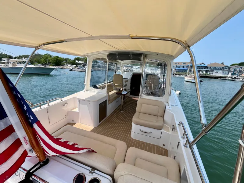 Slide: The Image of 2019 MJM 35z boat interior with seating, American flag, and waterfront view. - 9