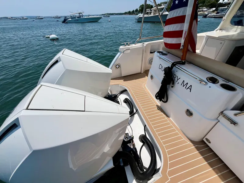Slide: The Image of 2019 MJM 35z boat with dual engines, docked in Duxbury, MA, featuring an American flag. - 7