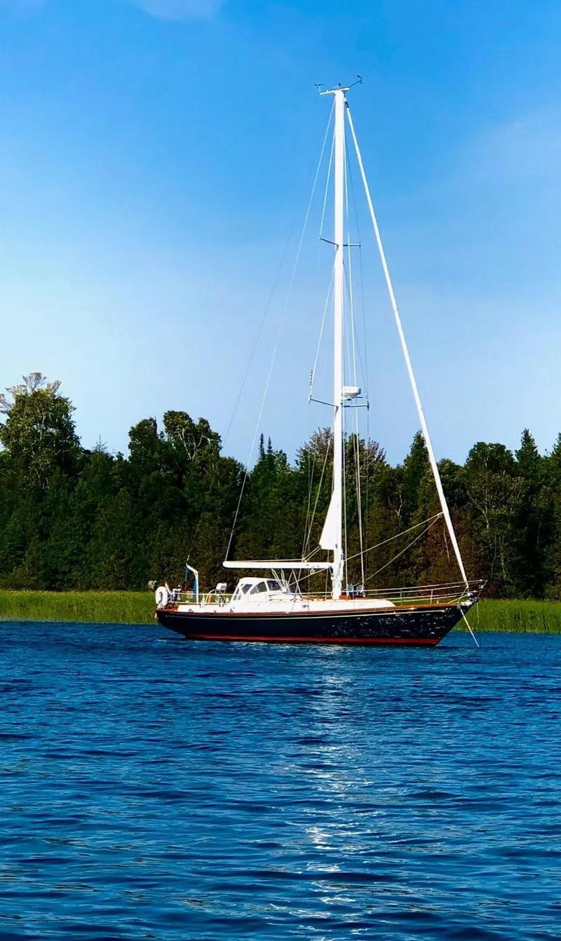 Slide: The Image of 1987 Hinckley Sou'wester 42 sailboat on calm water with forested shoreline. - 0