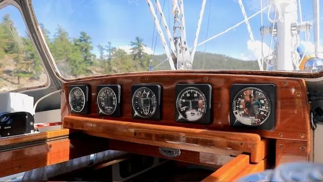 Slide: The Image of Hinckley Sou'wester 42 yacht dashboard with gauges, 1987 model, wooden finish, scenic background. - 5