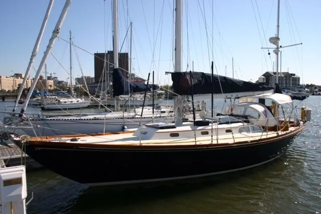 Slide: The Image of 1967 Hinckley Bermuda 40 sailboat docked in a marina, with clear skies and cityscape background. - 4