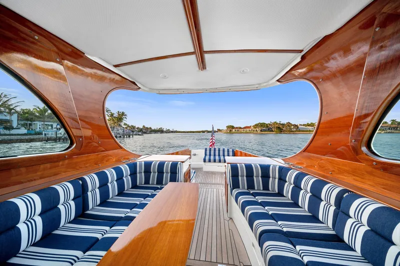 Slide: The Image of 2014 Hinckley Picnic Boat 37 MKIII interior with striped seating and wooden accents on the water. - 10