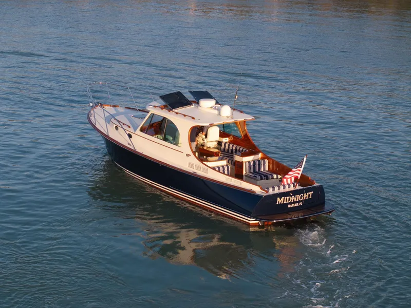 Slide: The Image of 2014 Hinckley Picnic Boat 37 MKIII cruising on calm waters, featuring elegant design and American flag. - 12