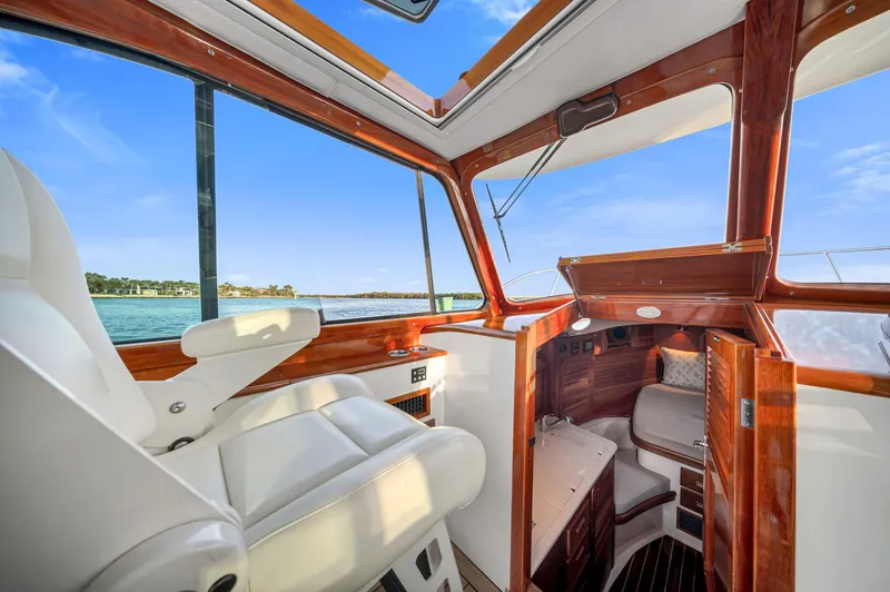 Slide: The Image of 2014 Hinckley Picnic Boat 37 MKIII interior with luxurious seating and wood finish, overlooking serene waters. - 6