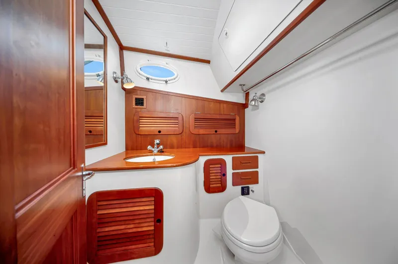 Slide: The Image of 2014 Hinckley Picnic Boat 37 MKIII bathroom with wooden cabinetry and porthole window. - 9