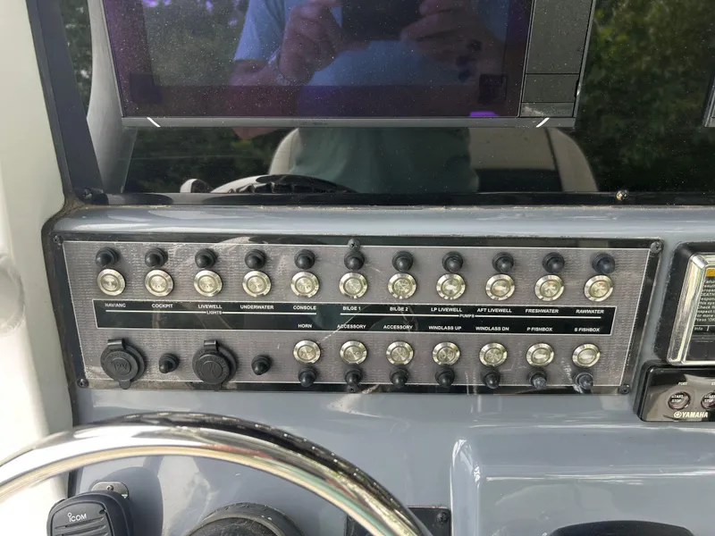 Slide: The Image of Control panel of 2020 Tidewater 272 CC Adventure boat with multiple switches and steering wheel. - 16