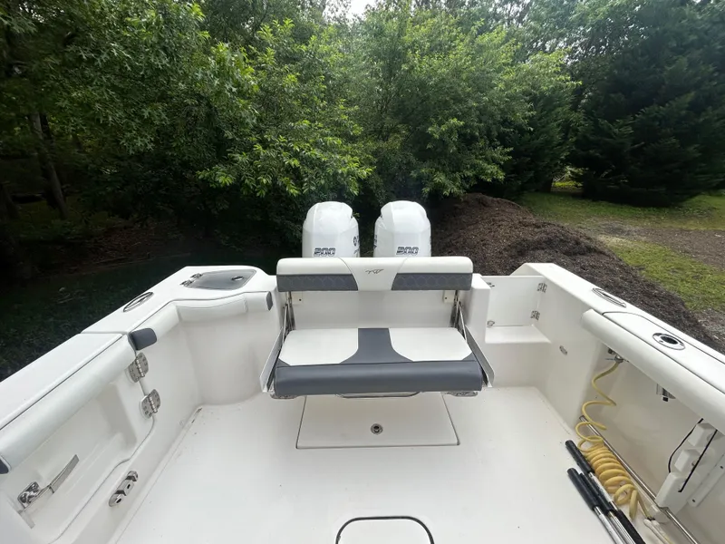 Slide: The Image of 2020 Tidewater 272 CC Adventure boat interior with dual engines and seating, surrounded by greenery. - 26