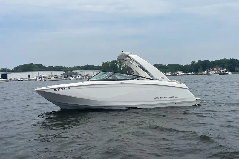 Slide: The Image of 2022 Regal FasDeck boat on a calm lake with marina in background. - 0
