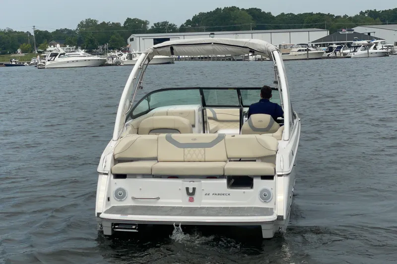 Slide: The Image of 2022 Regal FasDeck boat interior with beige seating and speakers, docked by the water. - 3