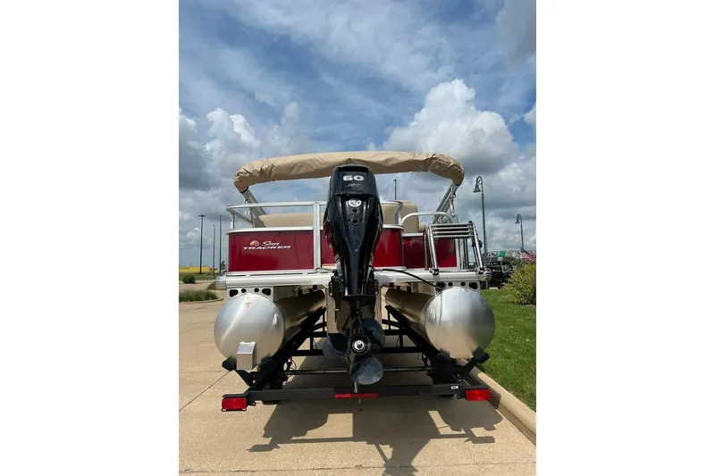 Slide: The Image of 2025 Sun Tracker Party Barge 18 DLX pontoon boat with outboard motor, parked outdoors. - 3
