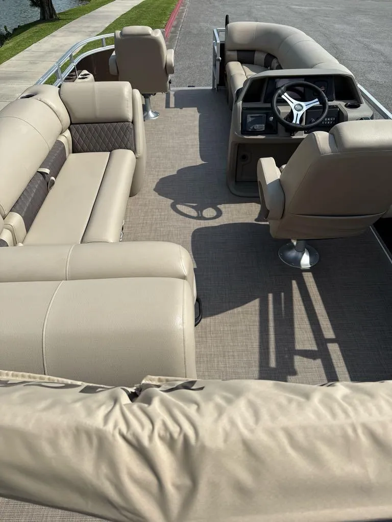 Slide: The Image of 2025 Sun Tracker SportFish 20 DLX pontoon boat interior with beige seating and steering console. - 4