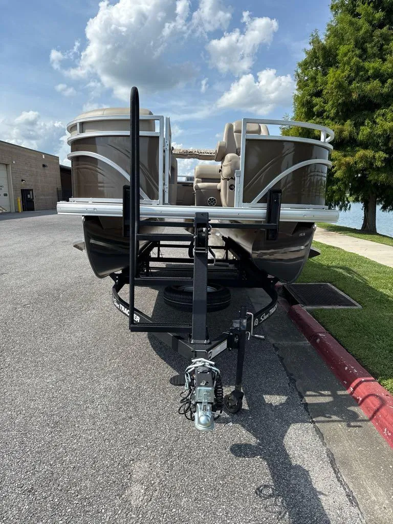 Slide: The Image of 2025 Sun Tracker SportFish 20 DLX pontoon boat on trailer, parked near water. - 5
