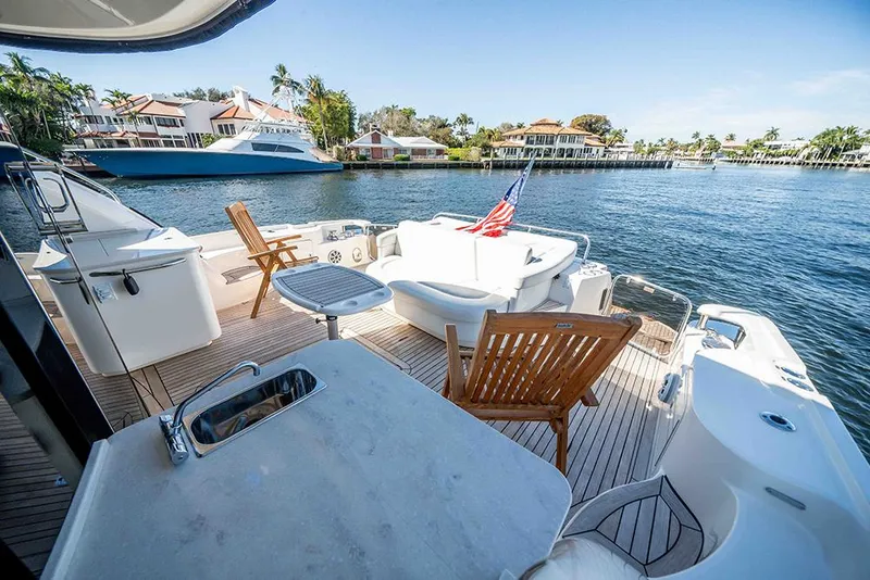 Slide: The Image of Luxurious 2012 Sea Ray 610 Sundancer yacht deck with seating, table, and scenic waterfront view. - 13