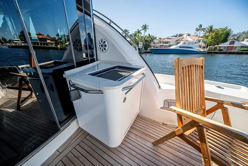 Slide: The Image of 2012 Sea Ray 610 Sundancer yacht deck with grill and wooden chair by waterfront homes. - 15