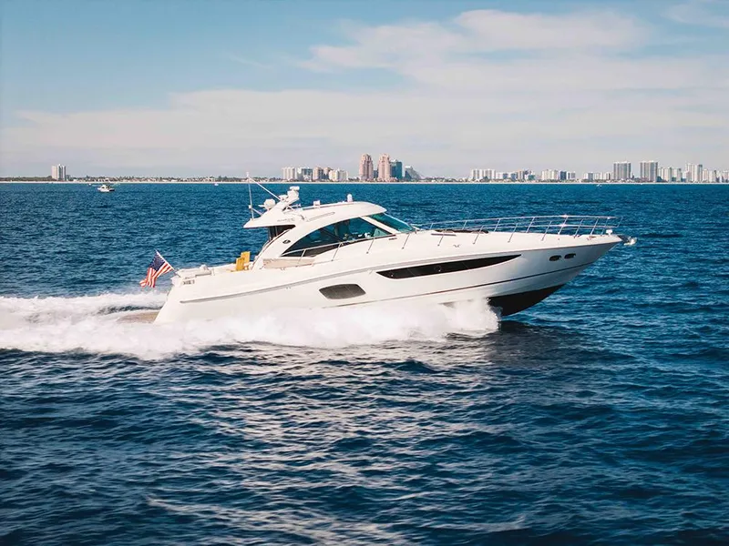 Slide: The Image of 2012 Sea Ray 610 Sundancer yacht cruising on open water with city skyline in background. - 24