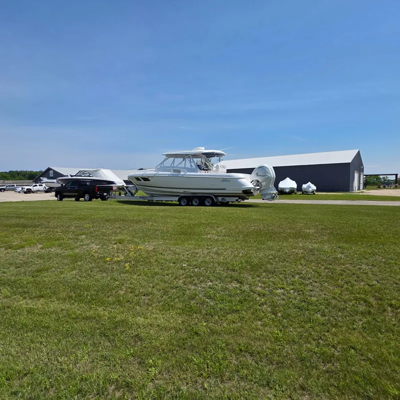 Slide: The Image of 2021 Intrepid 345 Valor boat on trailer, parked on grassy field near buildings. - 10