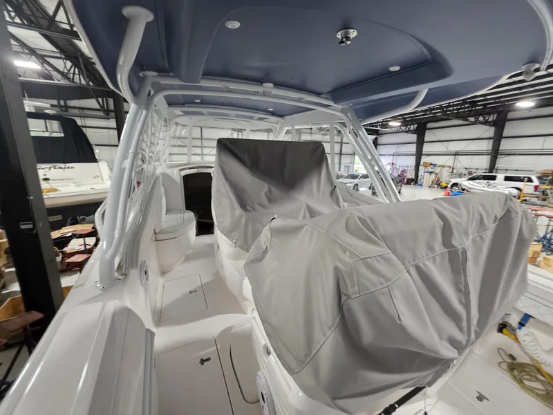 Slide: The Image of 2021 Intrepid 345 Valor boat interior with covered seating in a warehouse. - 13