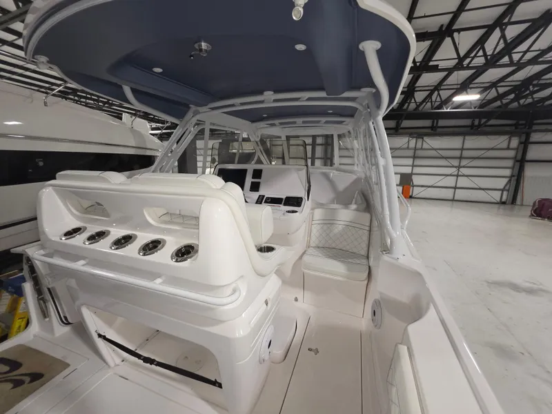 Slide: The Image of 2021 Intrepid 345 Valor boat interior with seating and control panel in a warehouse. - 14