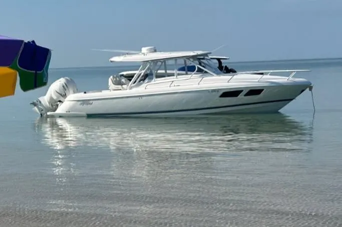 Slide: The Image of 2021 Intrepid 345 Valor boat anchored on clear blue water near a forested shoreline. - 2