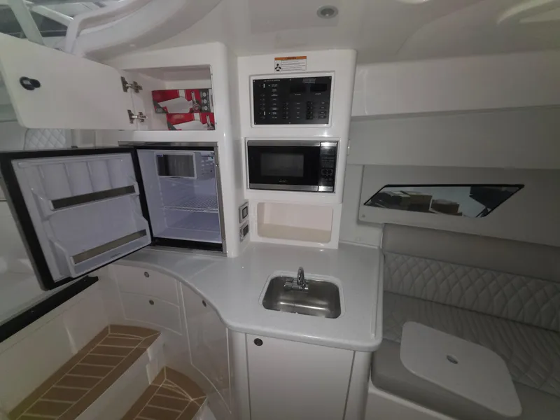 Slide: The Image of 2021 Intrepid 345 Valor interior with kitchenette, featuring fridge, microwave, sink, and seating area. - 24