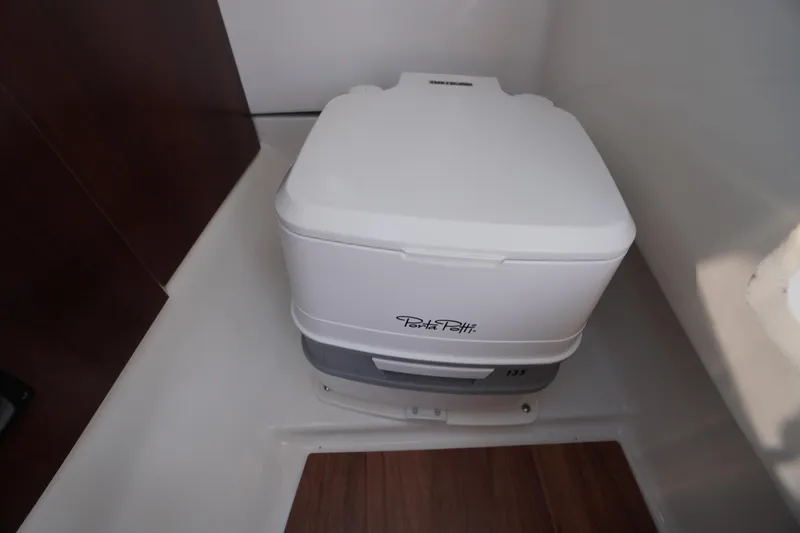 Slide: The Image of 2025 Chaparral 267 SSX boat interior with sink, porthole, and compact toilet. - 42