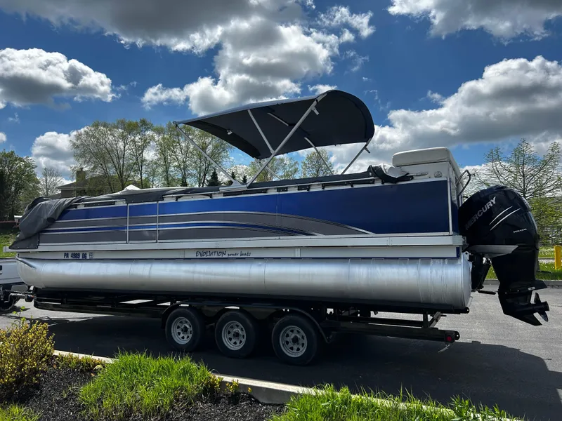Slide: The Image of 2005 Evolution 26 pontoon boat on trailer under cloudy sky. - 10