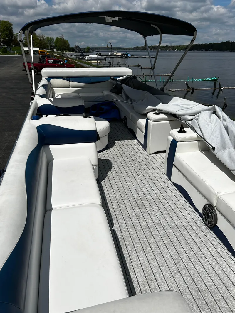 Slide: The Image of 2005 Evolution 26 boat with spacious seating, docked by a scenic lake. - 3