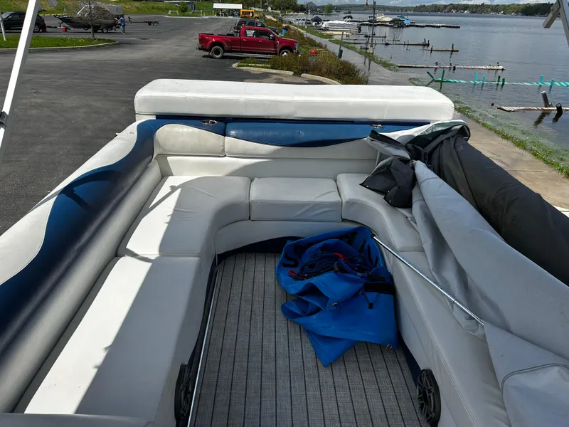 Slide: The Image of 2005 Evolution 26 boat with spacious seating, docked by a scenic lakeside. - 5