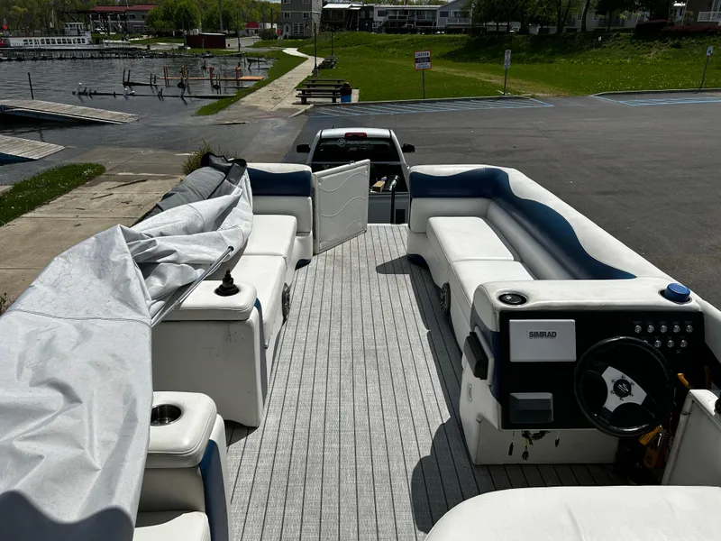 Slide: The Image of Pontoon boat interior with white seating, docked near a lake, Evolution 26 model, 2005. - 7