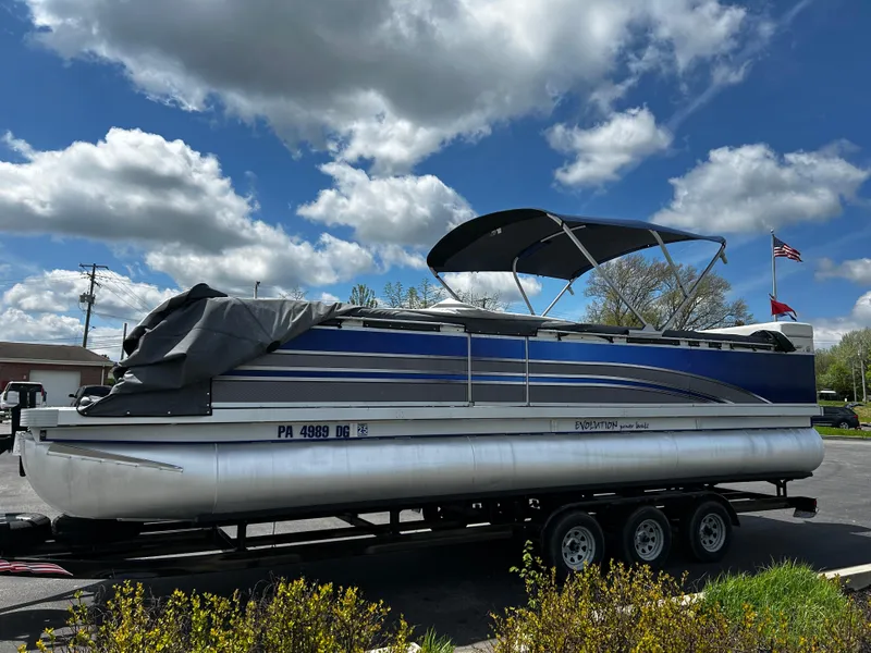 Slide: The Image of 2005 Evolution 26 pontoon boat on trailer under cloudy sky. - 9