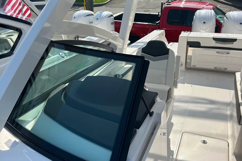 Slide: The Image of 2025 Robalo R257 Dual Console boat interior with seating and dashboard, parked near red truck. - 7