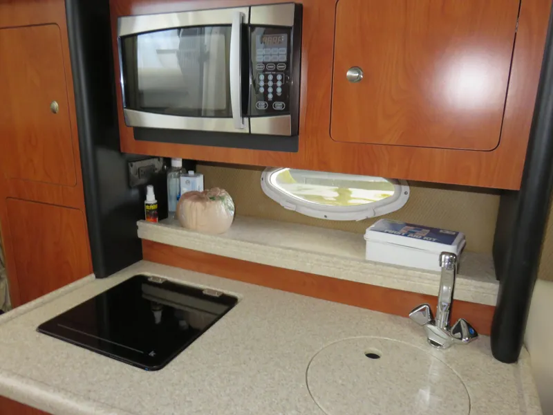 Slide: The Image of 2008 Rinker 280 Express Cruiser kitchen with microwave, stove, and sink. - 12