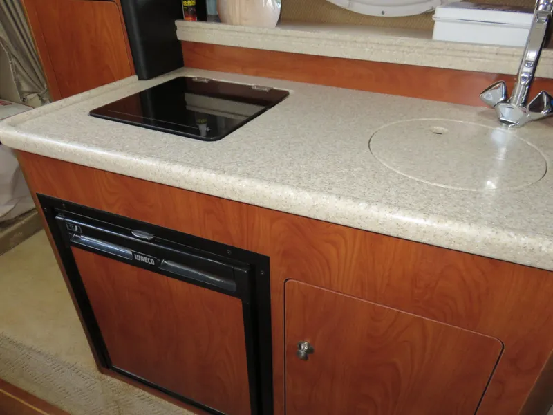 Slide: The Image of 2008 Rinker 280 Express Cruiser kitchenette with stove, sink, and mini fridge. - 13