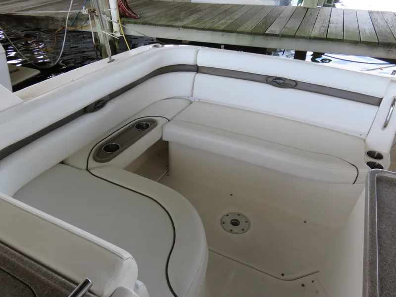 Slide: The Image of 2008 Rinker 280 Express Cruiser interior seating with cup holders, docked by wooden pier. - 19