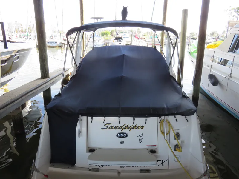 Slide: The Image of 2008 Rinker 280 Express Cruiser docked with cover, named "Sandpiper." - 27