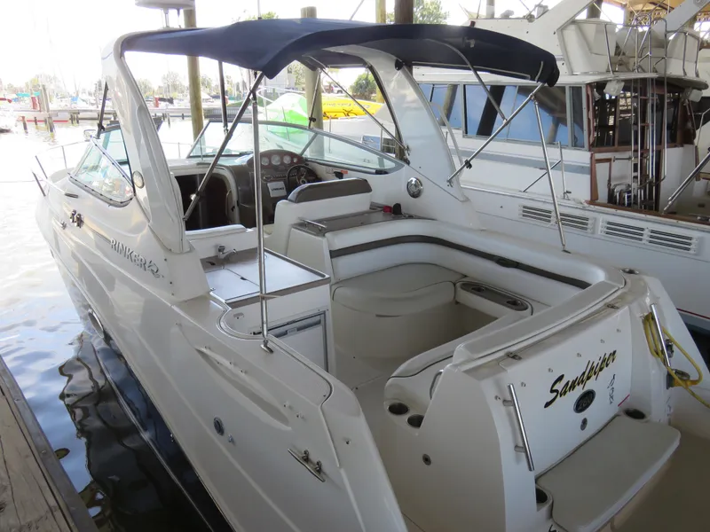 Slide: The Image of 2008 Rinker 280 Express Cruiser docked, featuring spacious seating and a navy canopy. - 4