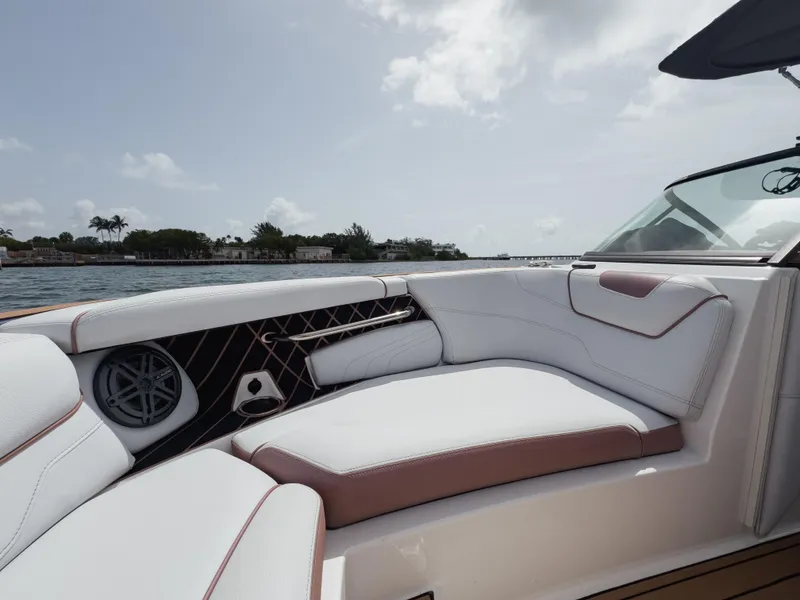 Slide: The Image of 2019 Nautique Super Air Nautique GS24 boat interior with white and brown seating, near water. - 39